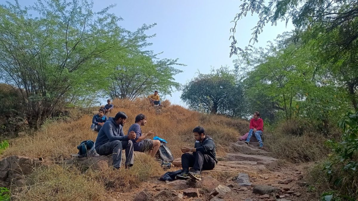 Walkers sitting together on rocks and dry grass on a hillside, talking